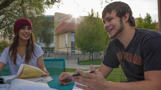 两个学生坐在外面的桌子旁聊天.